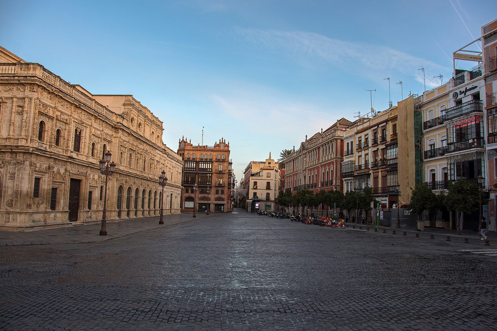 The carved town hall and tall old houses around an empty, cobbled square in early morning light.